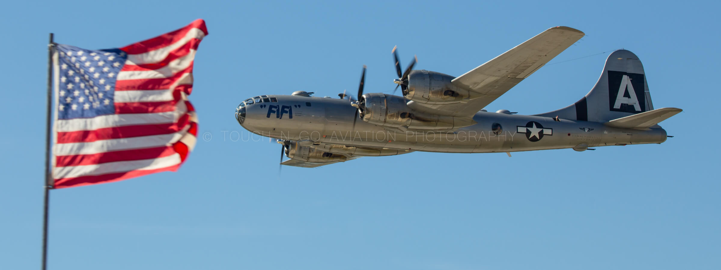 Fifi Boeing B-29 airborne at an airshow with the US flag in the foreground.