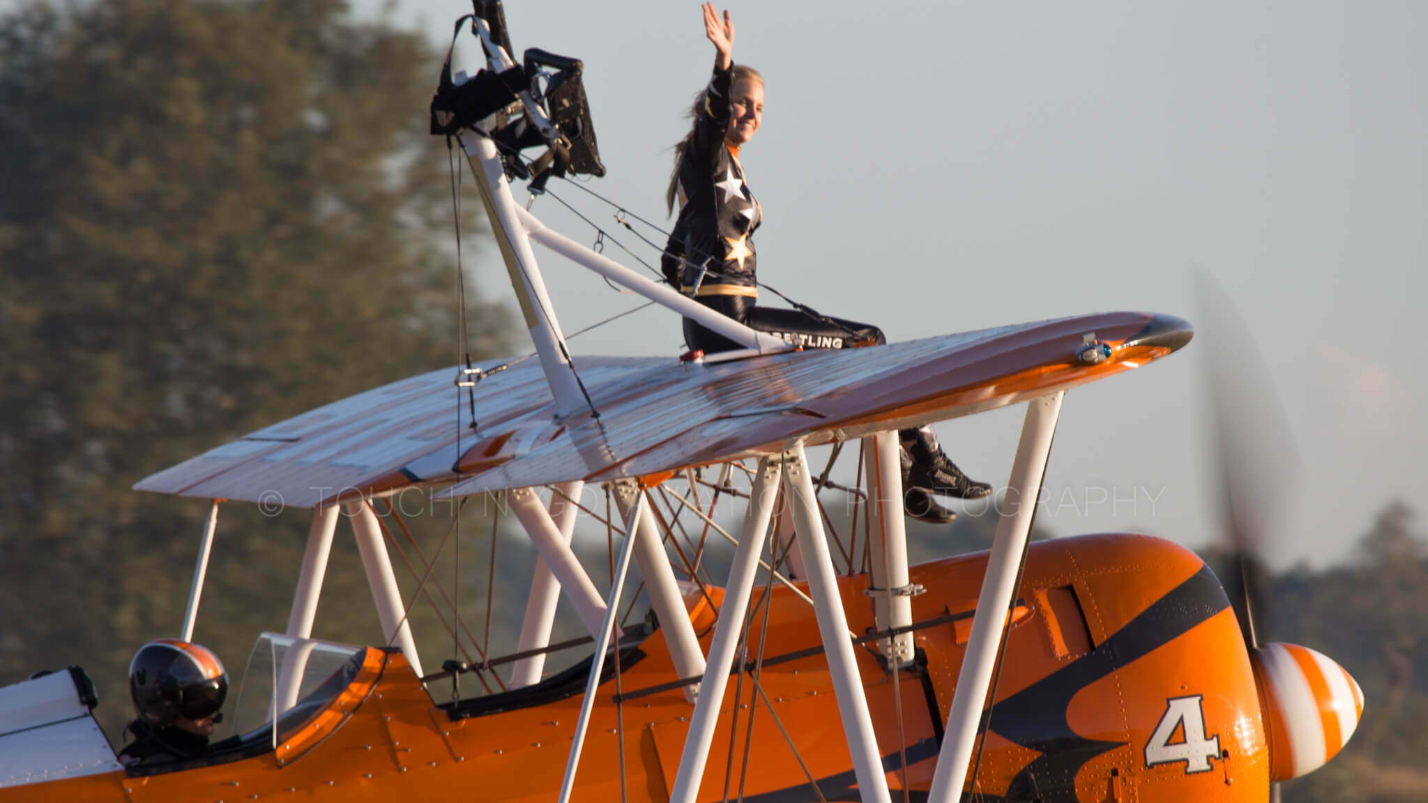 Breitling wingwalker waving to the crowd as the plane taxis for departure.
