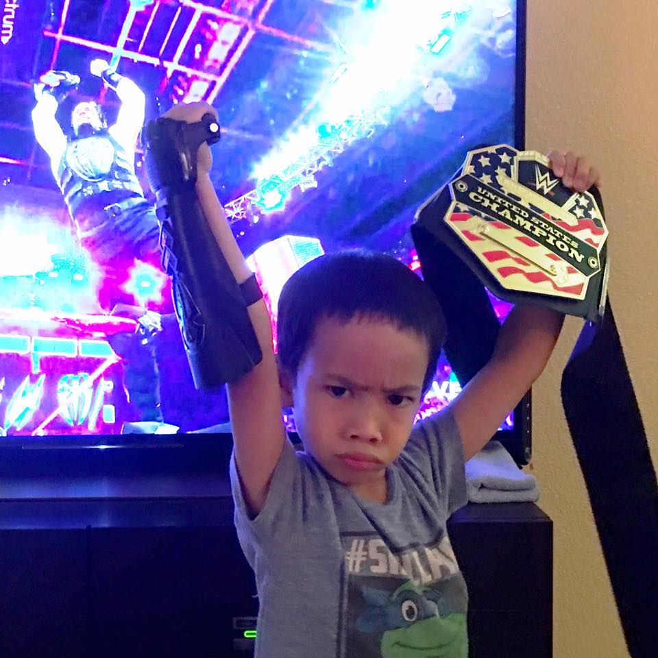 Kekoa standing in front of the tv posing like a wrestling champion.