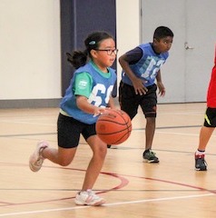 Rhiannon running down the basketball court dribbling a basketball