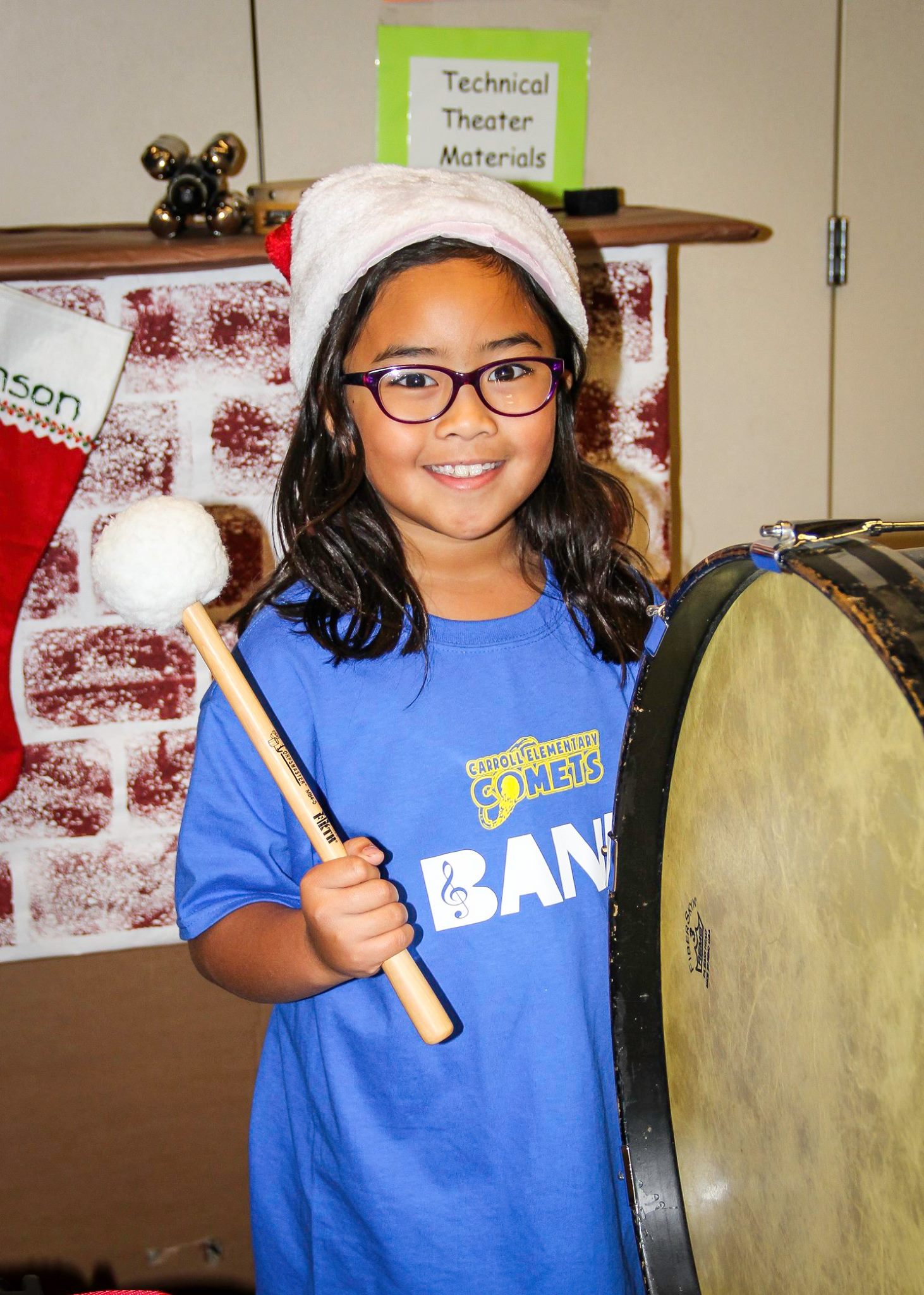 Rhiannon wearing a santa hat, posing with her drum